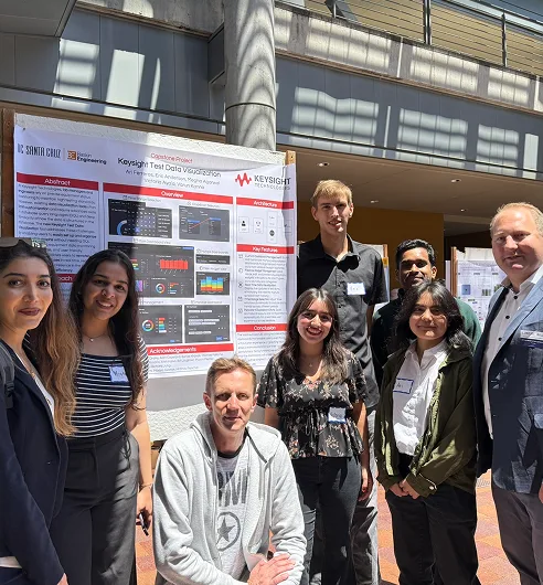 A capstone team gathered in front of their Keysight project poster.