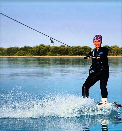 A rider skimming across a lake on a board, towed by a cable.